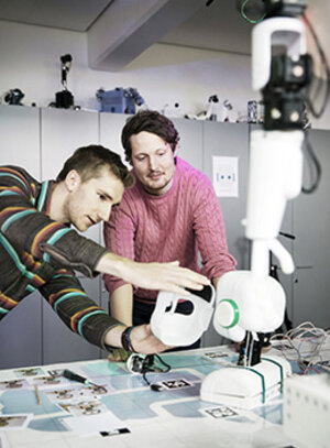 Två studenter undersöker en robot