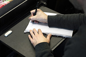 Hand som skriver på papper. Foto.