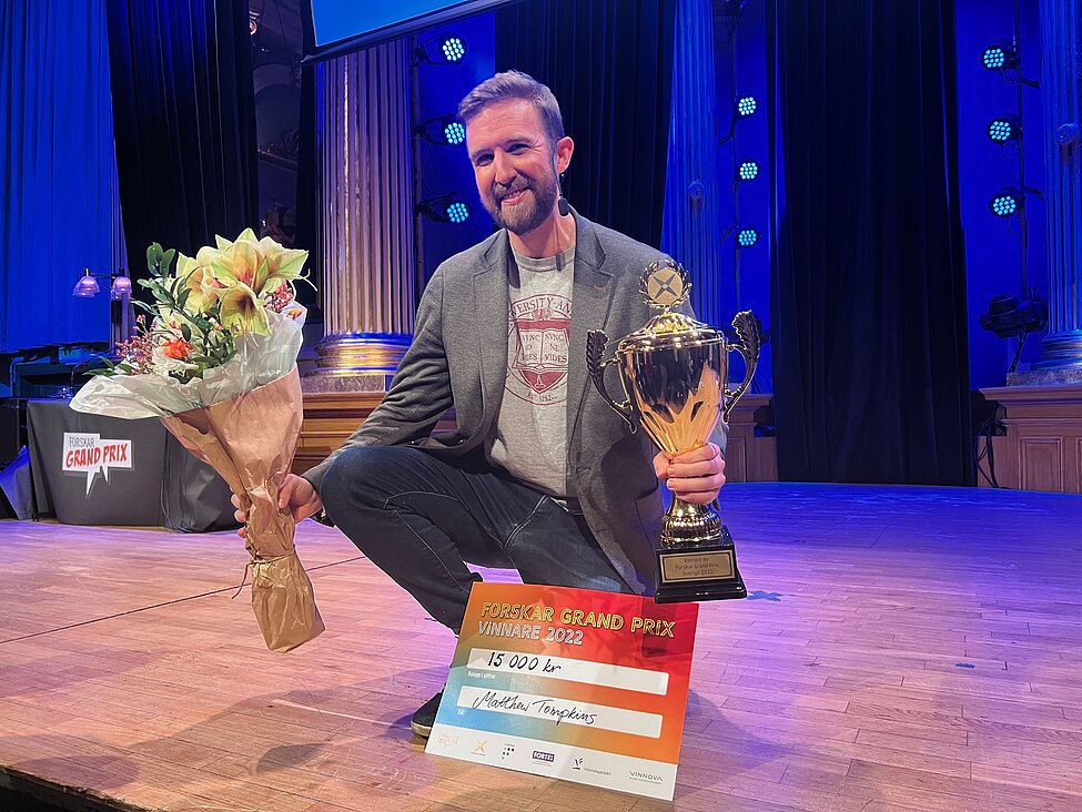 Matthew Tompkins på Forskar Grand Prix scen efter att han tagit emot diplom och blommor.