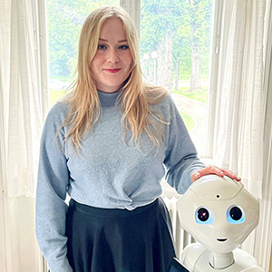 Julia Rosén bredvid en robot. Foto.